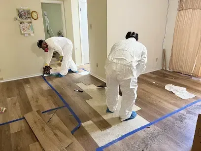 Crew in protective suits lifting soaked flooring after a water loss