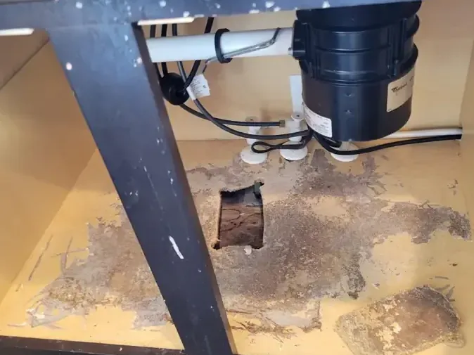 Sink base cabinet with an access hole cut beneath the plumbing to dry the cavity