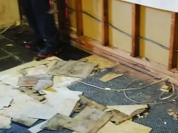Soaked flooring pulled up and the lower wall opened after floodwater came inside