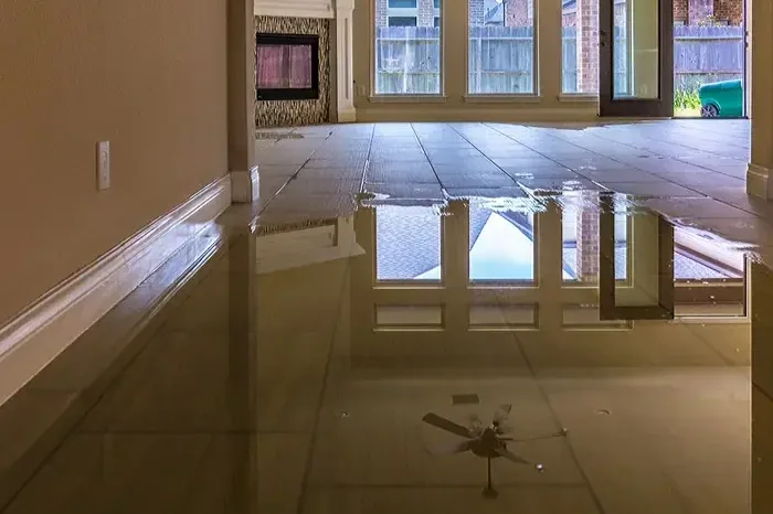 Standing floodwater on a tiled living room floor reflecting the windows