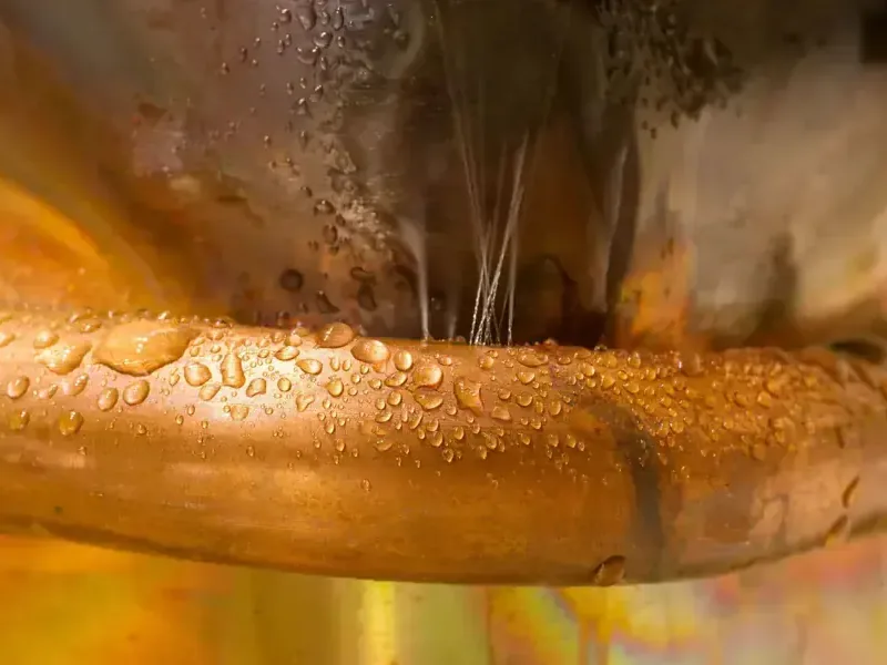 Water spraying out of a leaking copper supply pipe