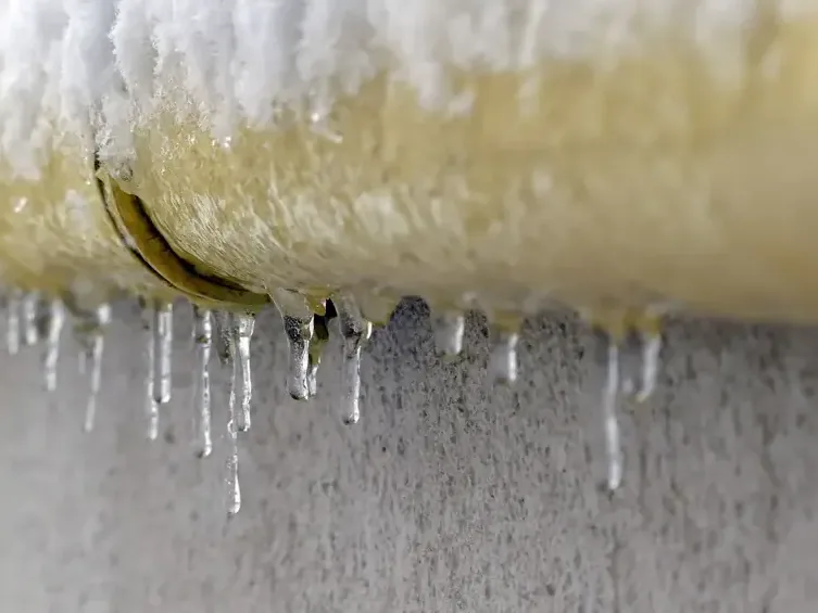 Frost-coated supply pipe with a split seam and icicles hanging after a hard freeze