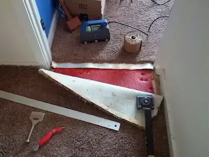 Carpet and pad rolled back while an air mover dries the floor above a hidden leak